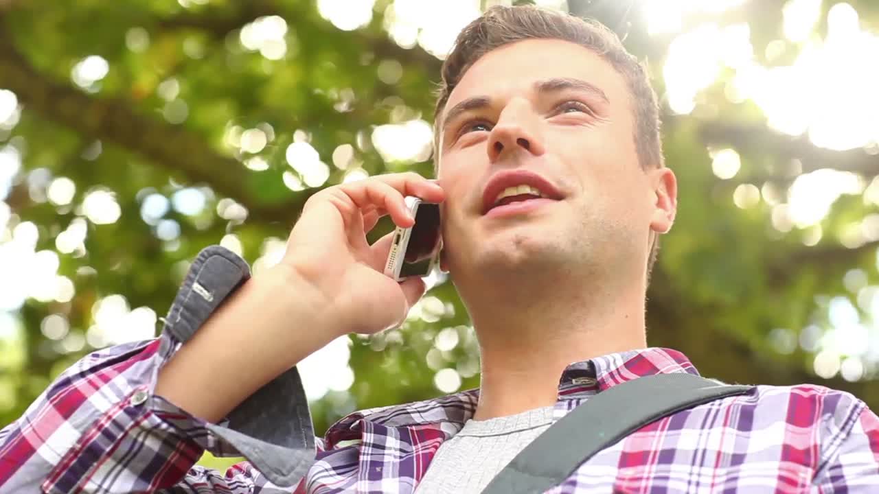 웃는 학생 이 밖 에 서서 전화 로 이야기 하고 있다