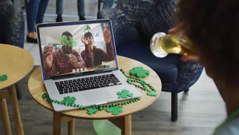 pareja sonriente y diversa que usa artículos en forma de trébol en una videollamada en una computadora portátil