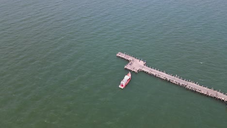 Aerial-descending-footage-of-the-Pattaya-Fishing-Dock-with-a-fishing-boat-docked-and-moving-with-the-waves,-Pattaya,-Thailand