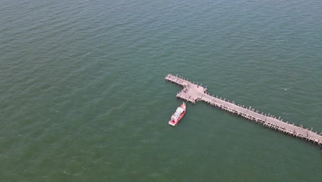 imágenes aéreas descendentes del muelle pesquero de pattaya con un barco pesquero atracado y moviéndose con las olas, pattaya, tailandia
