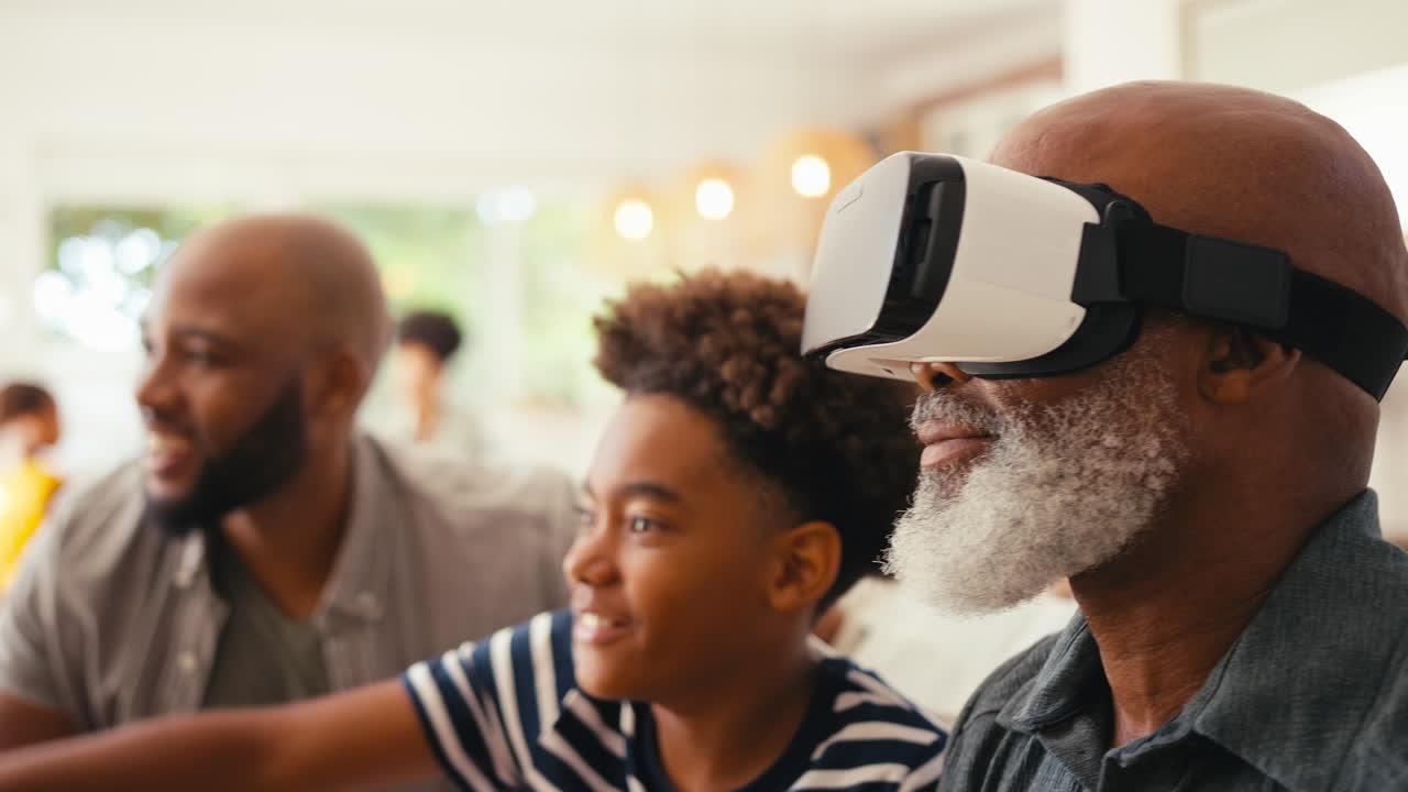 Grandfather Wearing VR Headset As Multi-Generation Male Family Sit On Sofa At Home Together