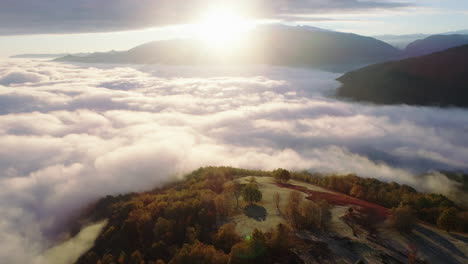 Volando-Sobre-Una-Colina-Hacia-Un-Océano-De-Nubes-Que-Cubren-El-Valle-De-Abajo