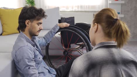 depressed disabled young man and his girlfriend are chatting at home.