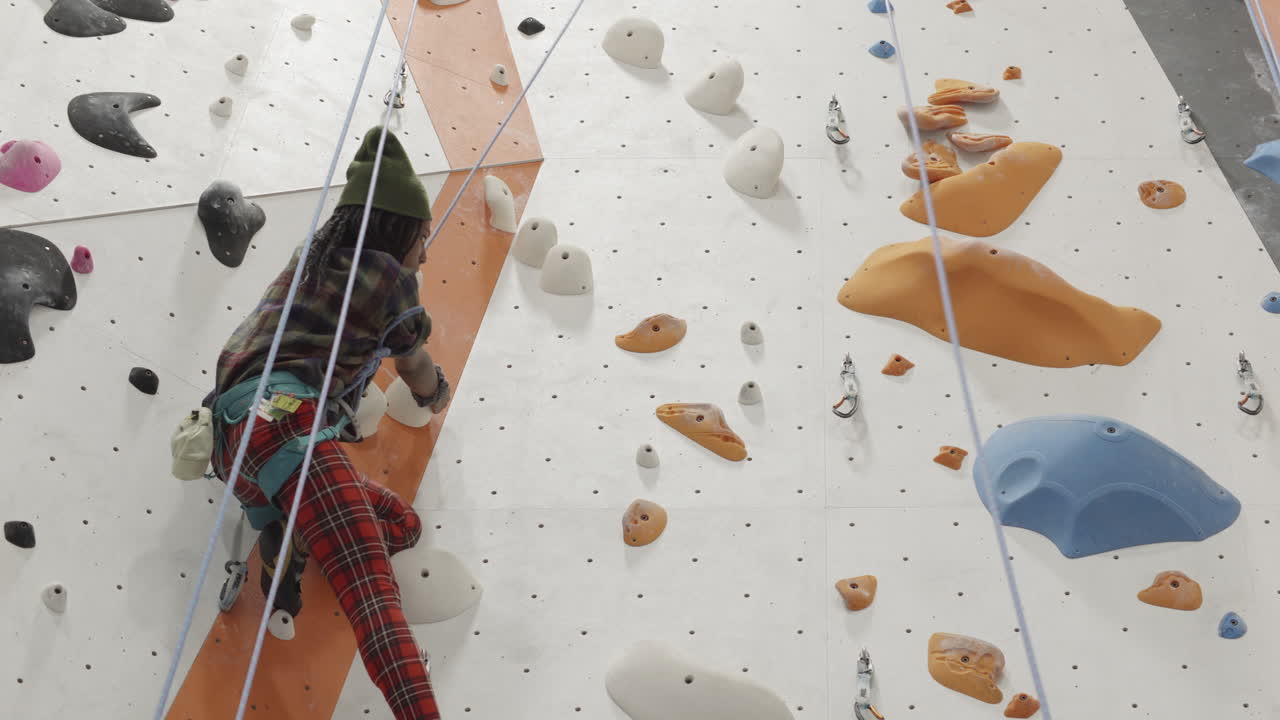 A young climber demonstrates good footwork technique as she scales a moderately challenging rock climbing wall with relative ease