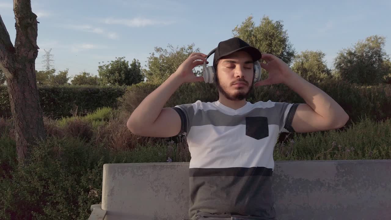 Young man listening music sitting in a park
