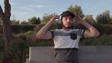 young man listening music sitting in a park