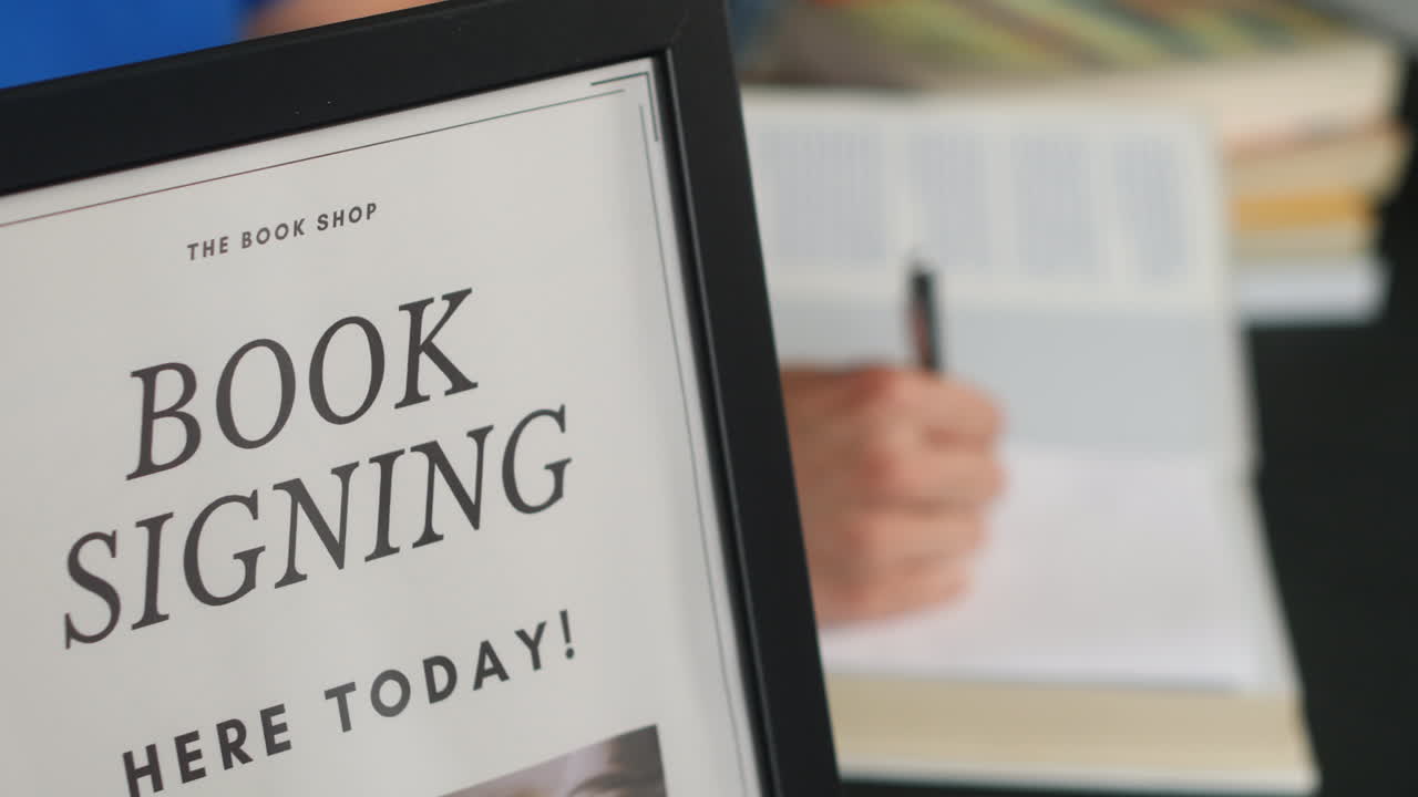 vista lateral de un autor irreconocible firmando libros en el lanzamiento de un libro