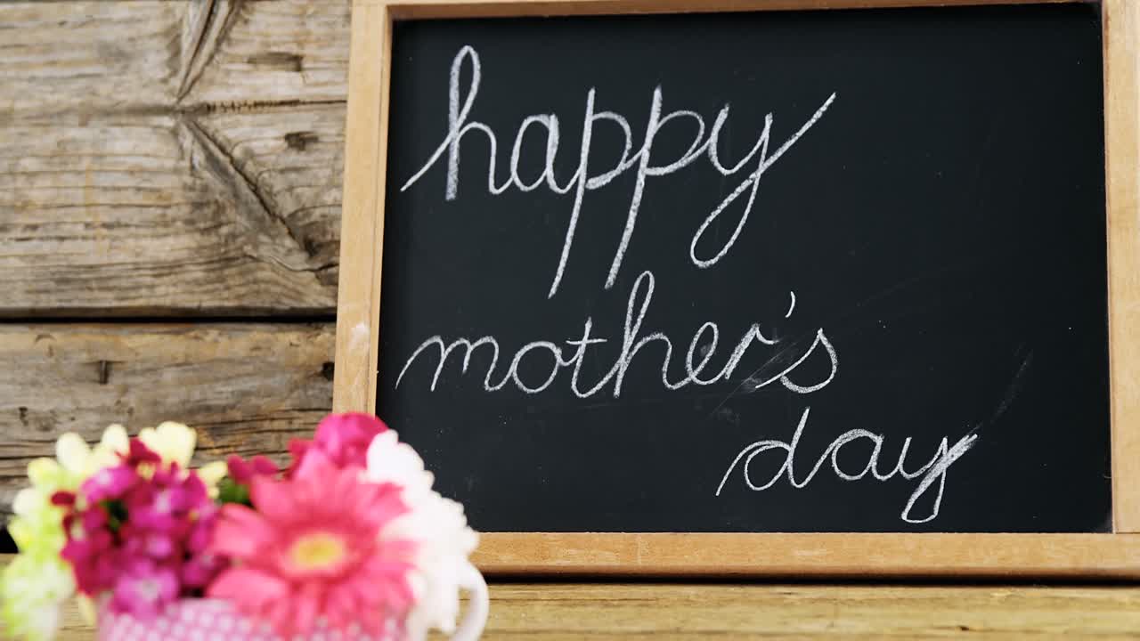 꽃 컵과 함께 크레이드 보드에 쓰여진 행복한 어머니의 날 텍스트