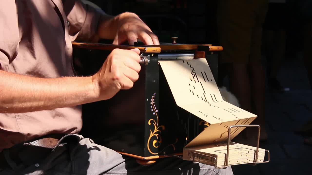 A street performer playing a mechanical hole punch music box on a sunny afternoon.
