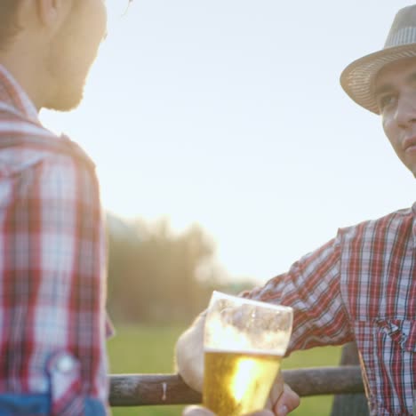 dos granjeros beben cerveza en la cerca de su rancho