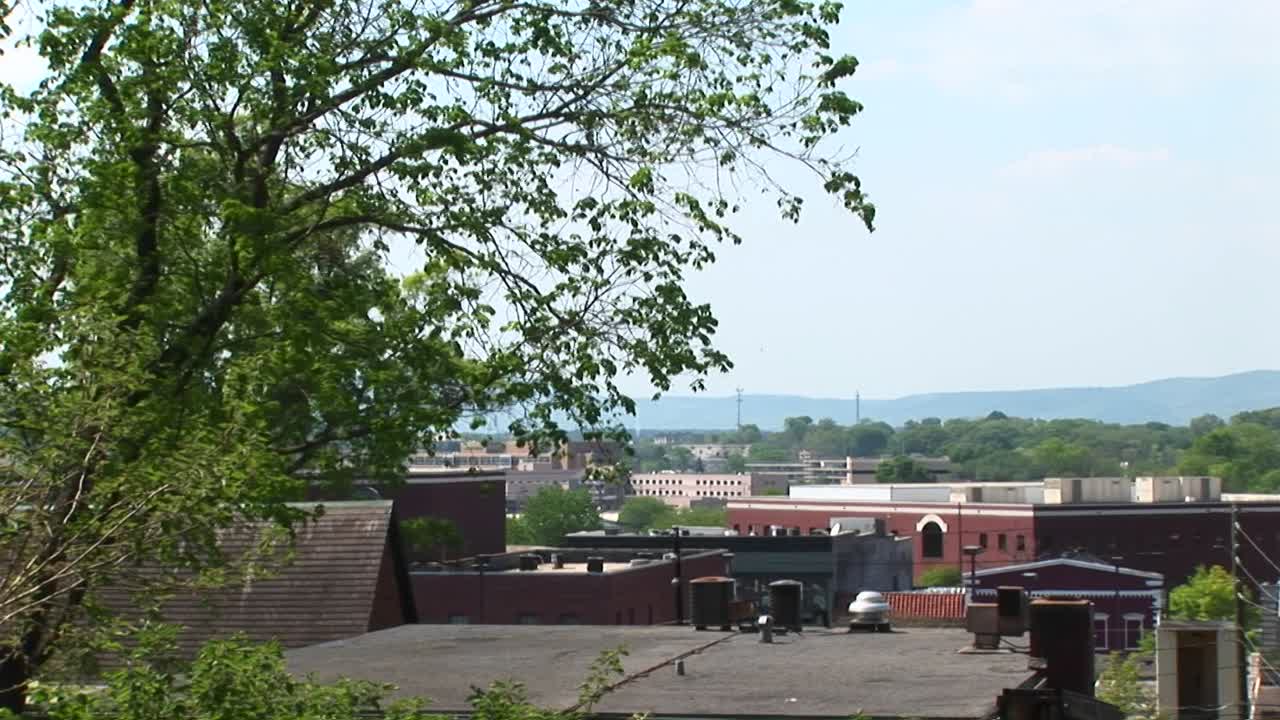 카메라가 작은 마을의 지붕선을 가로질러 오래된 시계탑을 강조 표시합니다.