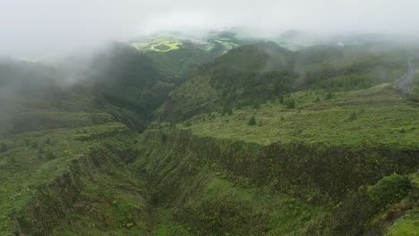 Lagoa-do-fogo,-a-lush-green-valley-covered-in-mist-on-sao-miguel-island,-aerial-view