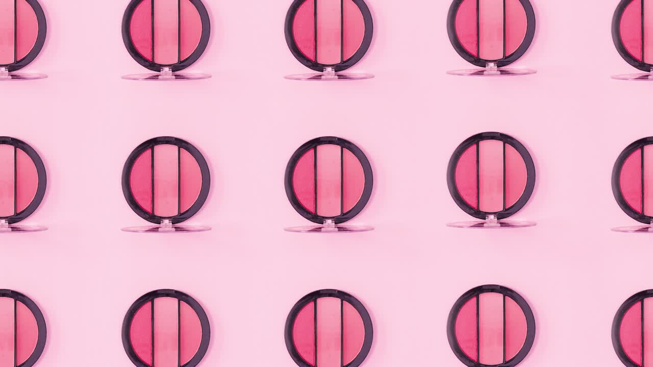 Beauty pattern made of Eye shadow palettes with pink shades rotate on pink background. Stop motion