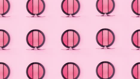 patrón de belleza hecho de paletas de sombra de ojos con tonos rosados girar en fondo rosado. detener el movimiento