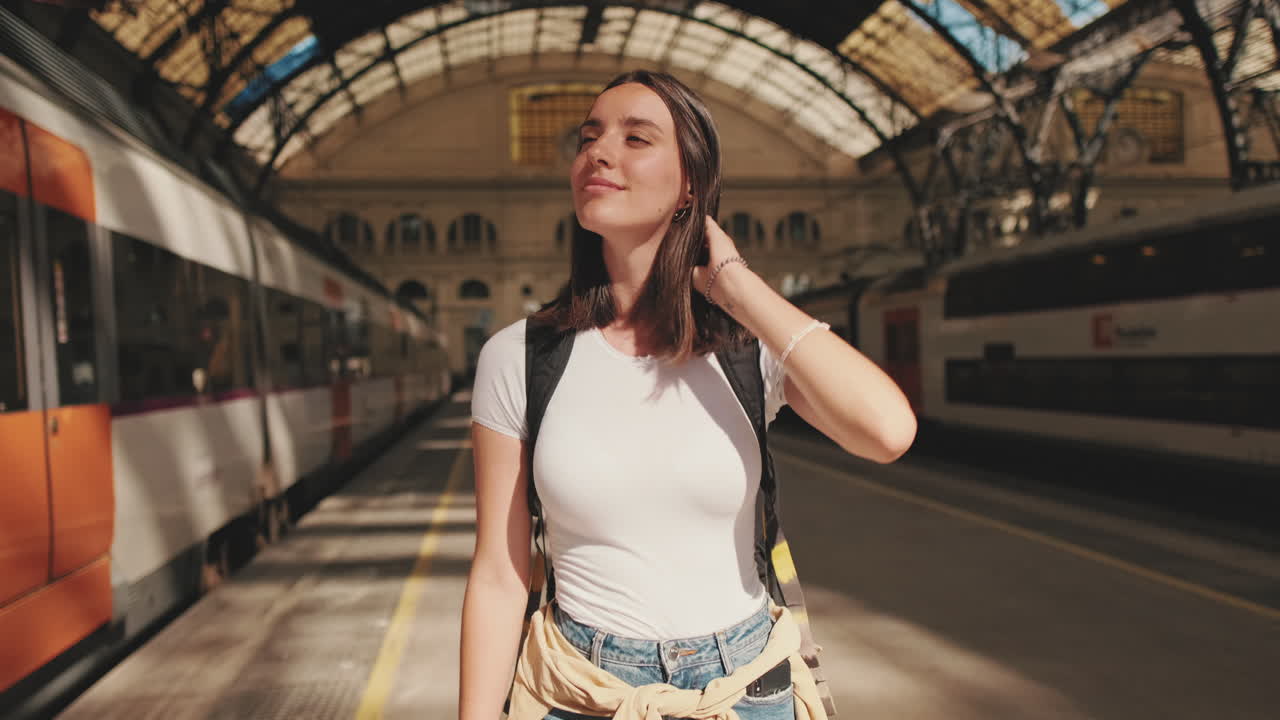 Giovane donna viaggiatrice in piedi sulla banchina della stazione ferroviaria