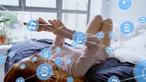 animation of network of digital icons over caucasian woman using smartphone lying on the bed at home