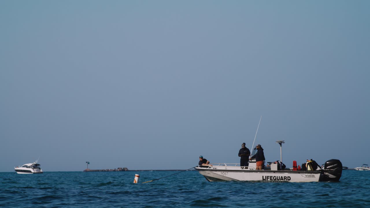 Scatto con teleobiettivo di 3 bagnini e una barca ancorata nel Lago Michigan.