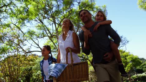 Familia-Caminando-En-El-Parque-Para-Hacer-Un-Picnic-En-Un-Día-Soleado-4k