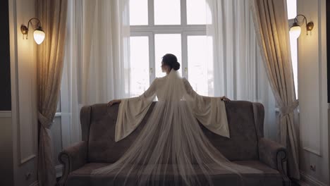 novia en vestido de boudoir cerca de la ventana, preparativos de la mañana de la boda, mujer en vestido y velo de noche