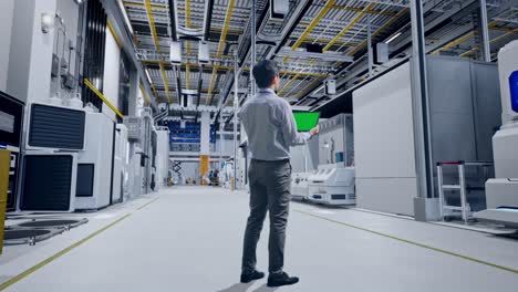 vista trasera del cuerpo completo de un trabajador profesional masculino asiático de pie con una tableta de pantalla verde en la digitalización de la fábrica