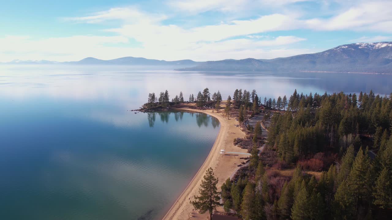 Lago Tahoe USA, veduta aerea della spiaggia e del parco di Sand Harbor, riflessi speculari di cielo e nuvole sull'acqua calma.