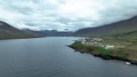 Ruhiges-Wasser-Des-Fjords-Nordfjördur-Mit-Der-Stadt-Neskaupstadur-Am-Berg-In-Ostisland