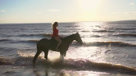 mujer a caballo en el océano al atardecer