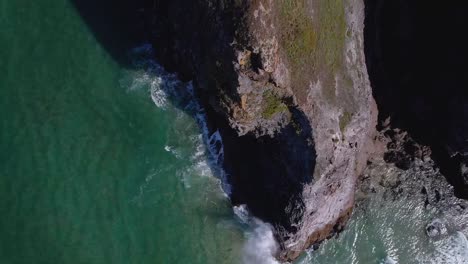 acantilados rocosos costeros de cornwall con olas del océano desde una toma aérea de dolly de arriba abajo