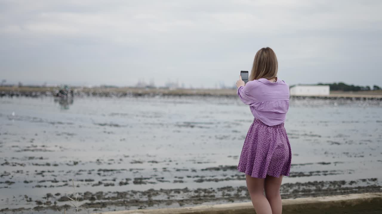 Woman Taking Photo of Birds over Water