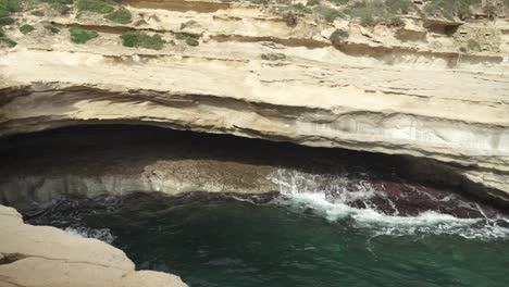 las olas del mar mediterráneo se precipitan de un lado a otro en la cueva de la playa de piedra de la piscina de san pedro