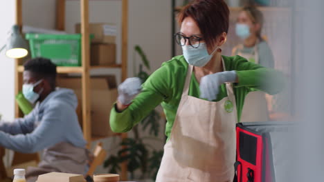 mujer con máscara empaquetando comidas y bebidas en una bolsa de entrega de alimentos