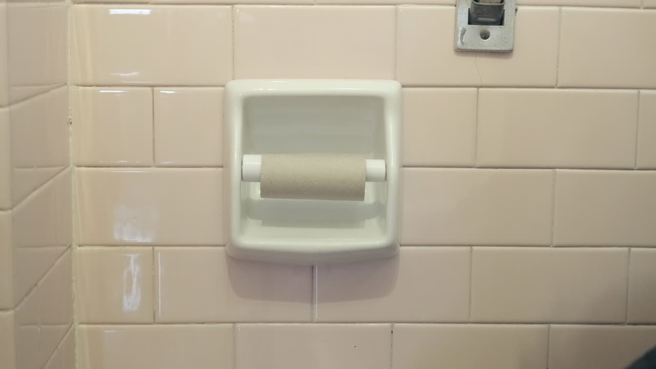 A man picks a strip of paper from a toilet roll and finds it's the last