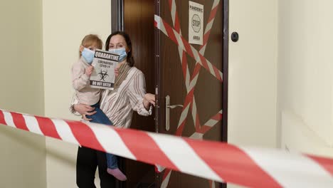 madre enferma con hija pequeña en máscaras médicas abriendo la puerta de la casa, cuarentena de coronavirus bloqueo