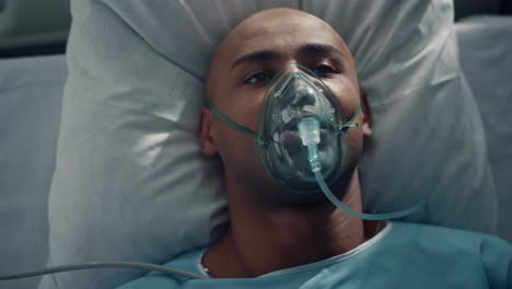 portrait patient breathing oxygen mask lying in bed hospital emergency unit.