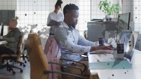 man working at desk with world map animation overlay in modern office