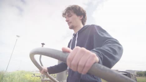 Young-adult-male-working-on-on-exercise-equipment-outdoors-in-good-weather