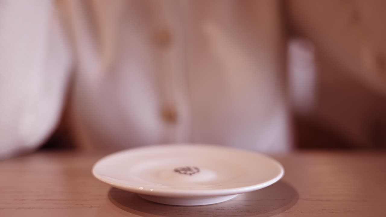 Woman drinking a coffee in a restaurant. World of coffee written on cup