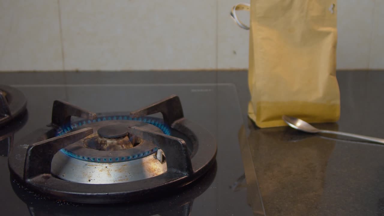 한 남자의 손이 가스레인지 위의 모카 냄비에 갓 끓인 커피를 꺼낸다