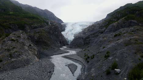 aerial view over a river towards a small, melting glacier in the tongass national forest, in alaska - rising, drone shot