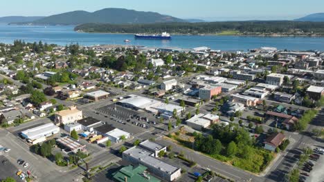 Aerial-hyperlapse-above-the-city-of-Anacortes,-WA-with-cars-zipping-through-the-streets-and-large-ships-moving-through-the-strait
