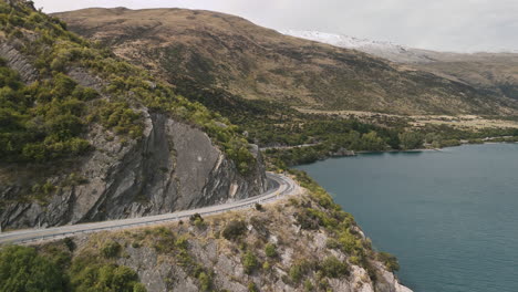 scenic mountain road winding along lake in new zealand