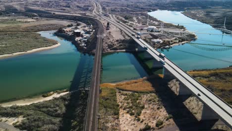 Autos-Und-Lastwagen-Fahren-über-Eine-Brücke-über-Den-Colorado-River,-Autobahn-I-40-Ost,-Lange-Schatten,-Sommer,-Weitwinkel-Drohne