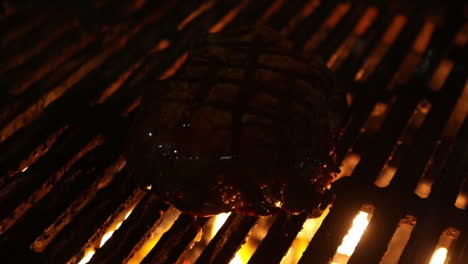 dark footage of a sizzling steak being basted on a gas fired grill by a chef