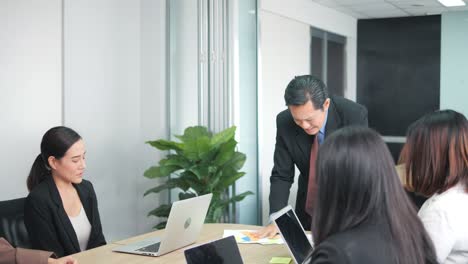 angry asian boss yelling at colleagues during a meeting with his team in a meeting room.