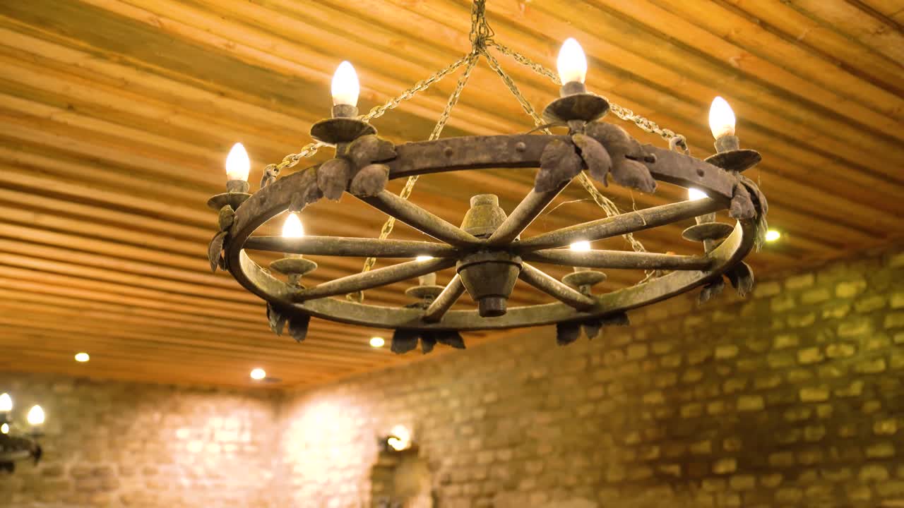 Rustic chandelier made from wagon wheel hangs from wooden ceiling