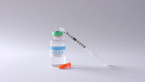 close up of insulin vial and syringe on grey background, slow motion