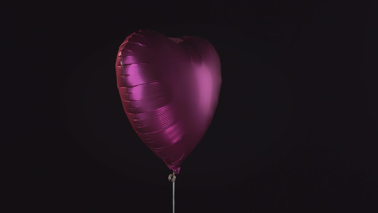 Bel palloncino rosa ad elio a forma di cuore con cuori rosa che cadono tutt'intorno.
