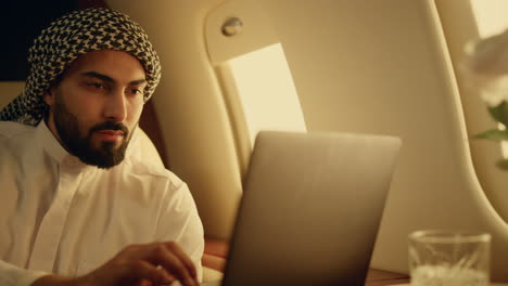 focused businessman using laptop on aircraft. serious man typing browsing web