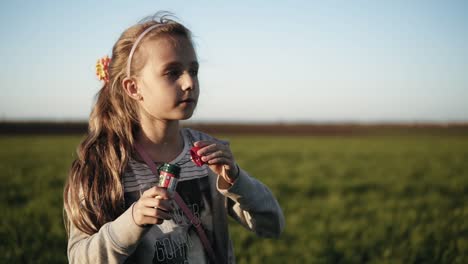 Schöne-Kleine-Frau-Mit-Langen-Blonden-Haaren,-Die-Draußen-Seifenblasen-Bläst.-Kaukasisch.-Ausgehende-Kamera.-Nahaufnahme