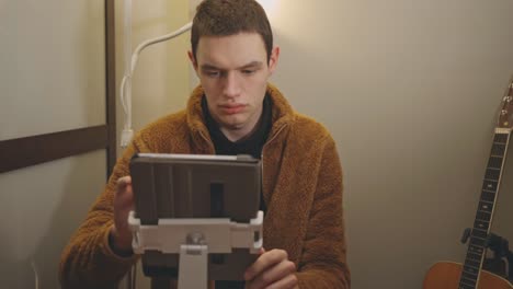 Young-Man-Using-And-Browsing-A-Tablet-Inside-A-Room---medium-shot